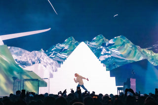 A man onstage in front of a glowing pyramid
